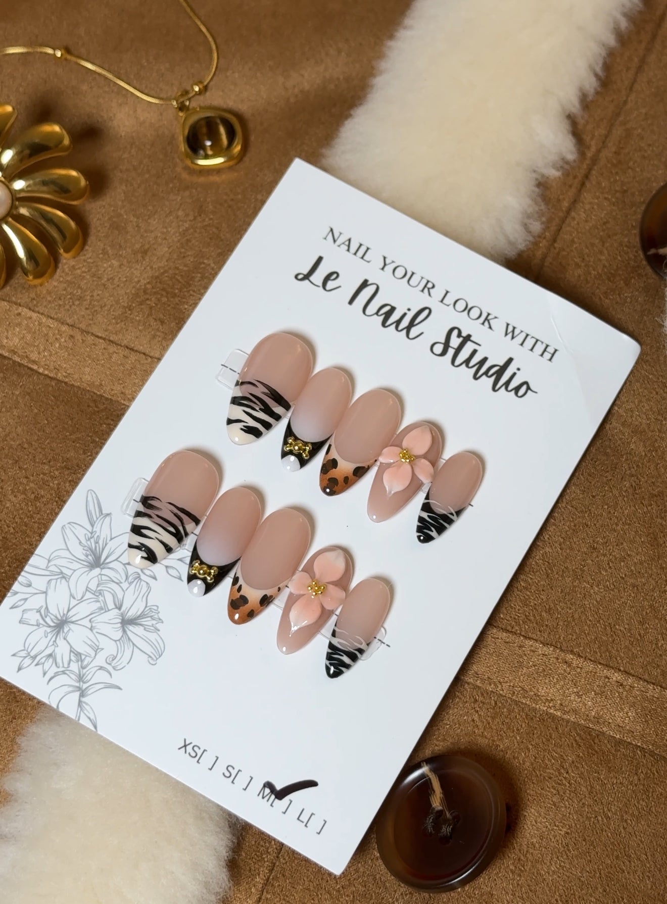 Press On Nail set with a nude base featuring zebra and leopard patterns, adorned with bows and gold details and 3D Gel Flower.
