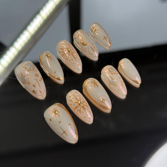 Celestial press on nail set with gold star and moon designs on nude shimmer base holiday vibes Christmas gift best nail for holiday cozy