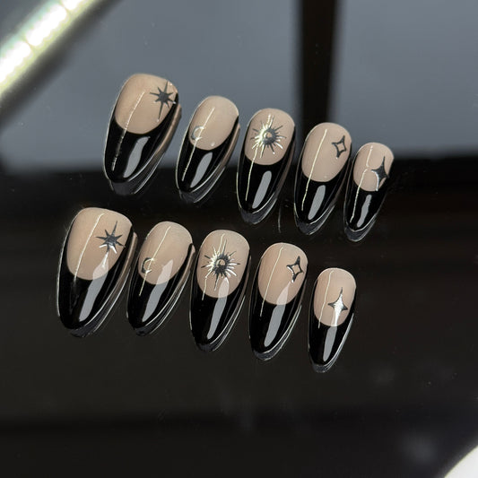 Handmade almond-shaped press on nail art set with sleek black designs and star accents on a neutral background.